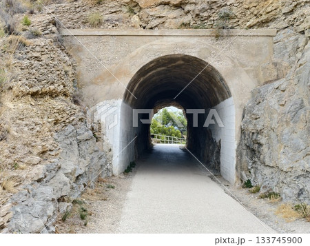 scenic rocky pathway, concrete arch over rocky hillside guides travelers to sunlit woods and clear scenic rocky pathway, concrete arch over rocky hillside guides travelers to sunlit woods and clear 133745900