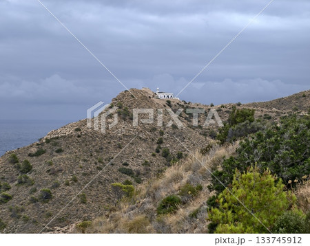 solitary church on rugged mountaintop, remote white chapel crowns dry hillside with moody atmosphere 133745912