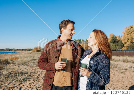 Happy beautiful couple in love enjoying autumn picnic on coast in open air. Weekend and lifestyle concept. High quality photo Happy beautiful couple in love enjoying autumn picnic on coast in open air. Weekend and lifestyle concept. High quality photo 133746123