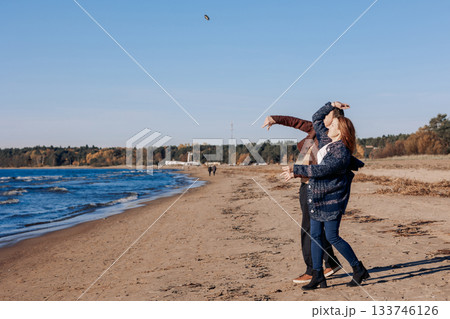 Young carefree couple in love throwing pebbles, shells, stones into sea outdoors. Fun family game together. High quality photo Young carefree couple in love throwing pebbles, shells, stones into sea outdoors. Fun family game together. High quality photo 133746126