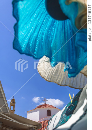 National white blue dress flutters in wind in old town of Lindos. Narrow streets with churches, white houses on island of Rhodes, Greece. High quality photo 133746137