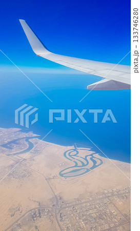 View from the window of plane on blue sky and earth with landscape of desert, sea and canals in Emirates. High quality photo 133746280