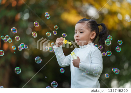happy toddler girl blowing soap bubbles in park happy toddler girl blowing soap bubbles in park 133746290