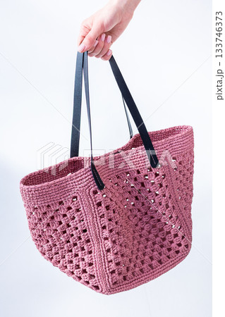 Female hand holding fashionable pink woven bag. Fashion and luxury accessories. Vertical photo. High quality photo 133746373