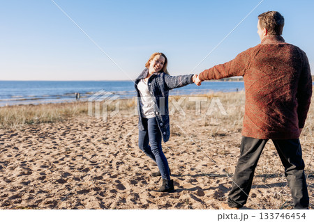 Loving couple walks on beach along sea on sunny autumn day. Weekend and lifestyle concept. High quality photo Loving couple walks on beach along sea on sunny autumn day. Weekend and lifestyle concept. High quality photo 133746454