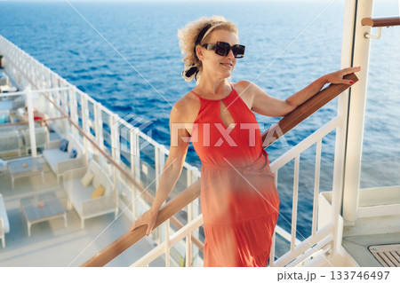 Beautiful happy woman on cruise ship deck. Elegant lady in red dress relaxing on vacation. Sea travel and summer holiday. High quality photo Beautiful happy woman on cruise ship deck. Elegant lady in red dress relaxing on vacation. Sea travel and summer holiday. High quality photo 133746497