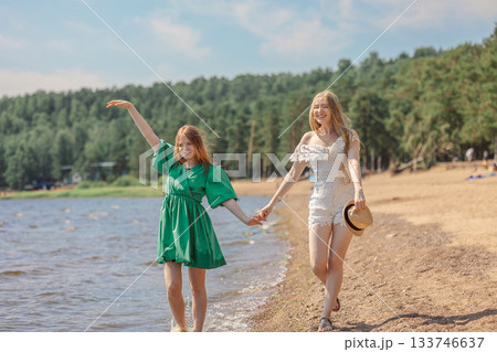 Smiling girls walking along coastline. Concept of friendship, entertainment and fun. High quality photo Smiling girls walking along coastline. Concept of friendship, entertainment and fun. High quality photo 133746637