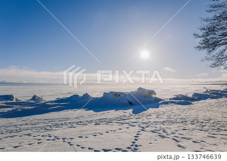 Winter landscape. Panoramic view of beautiful sunset on bay. Ice, snow and rocks on coastline. Setting sun in bright light. High quality photo Winter landscape. Panoramic view of beautiful sunset on bay. Ice, snow and rocks on coastline. Setting sun in bright light. High quality photo 133746639