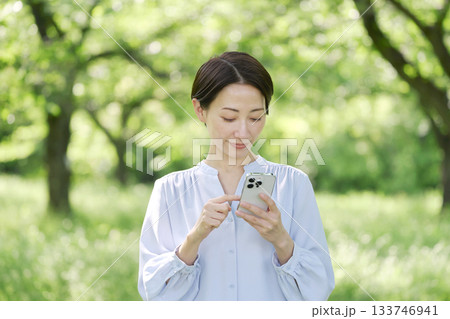 屋外でスマートフォンを使う40代女性 133746941