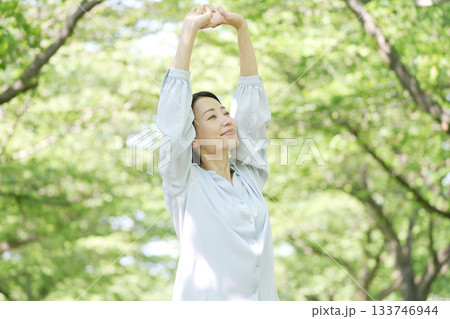 屋外で伸びをする40代女性 屋外で伸びをする40代女性 133746944