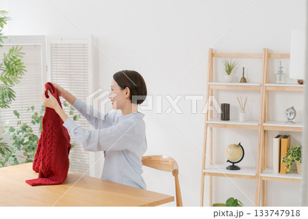 赤いセーターを広げる女性 133747918