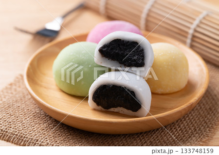 Daifuku mochi (Traditional Japanese sweet) stuffed with black sesame seed on wooden plate 133748159