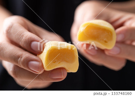 Daifuku mochi (Traditional Japanese sweet) stuffed with soybean paste holding by hand and eating 133748160