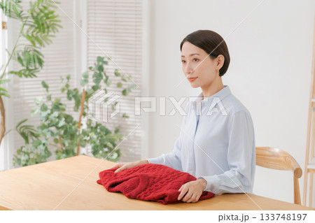 赤いセーターを広げる女性 133748197