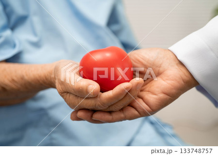 Asian woman doctor holding red heart with senior patient for health in hospital. Asian woman doctor holding red heart with senior patient for health in hospital. 133748757
