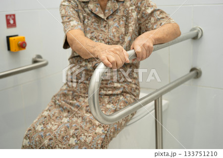 Asian elderly woman patient use toilet support rail in bathroom. Asian elderly woman patient use toilet support rail in bathroom. 133751210