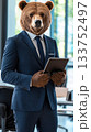 A confident brown bear stands in a well-lit modern office, dressed in a tailored navy-blue three-piece suit while holding a high-end tablet 133752497