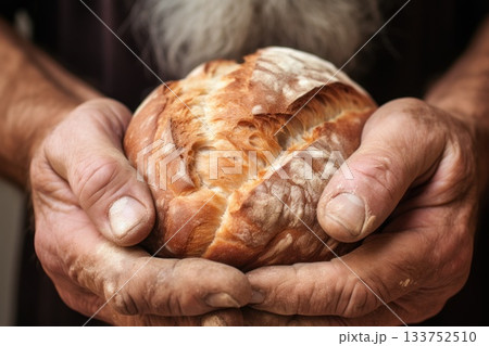 A close-up shot capturing seasoned hands cradling freshly baked bread, symbolizing tradition, craftsmanship, and the simple comforts of home-cooked nourishment. 133752510