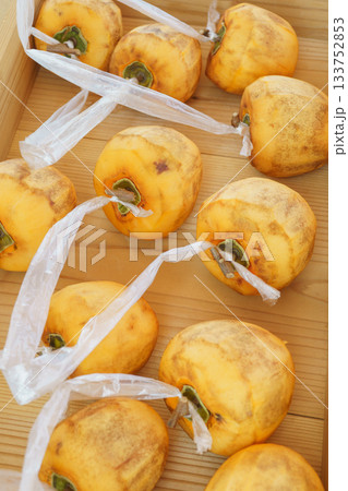 干し柿を作る・枝をT字型に残し皮を剥いた柿に紐をつける 133752853