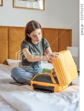 Woman packing yellow suitcase preparing for journey 133753151