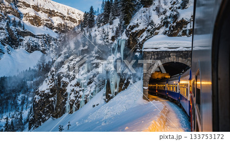 Train emerges from snowy mountain tunnel, surrounded by icy cliffs and pine trees, creating serene winter scene 133753172