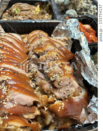 Jokbal, a Korean dish of braised pork hock, slow-cooked in a rich, savory sauce with soy, garlic, and spices. Tender and flavorful, it’s often served with lettuce wraps, garlic, and ssamjang 133754137