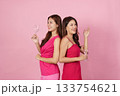 Party Fun. Two women enjoying a toast with glasses in matching pink outfits. 133754621