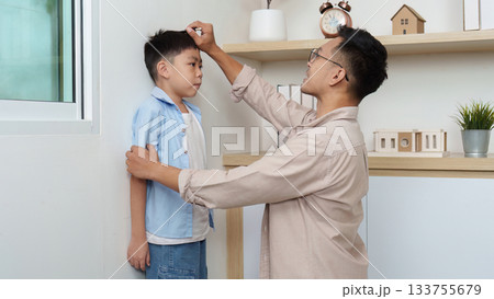 Family Life: Father measuring son's height at home Family Life: Father measuring son's height at home 133755679