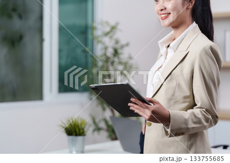 Working women smiling while holding tablet in modern office 133755685