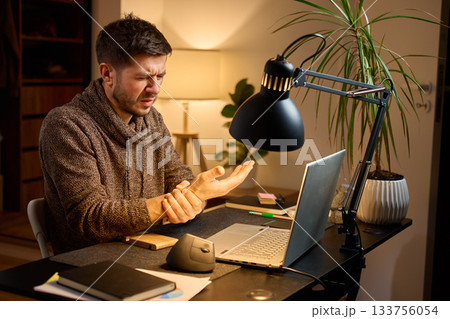 Man sitting at desk with wrist pain during remote work 133756054