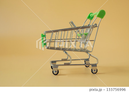 An empty tiny shopping cart on color background. 133756996
