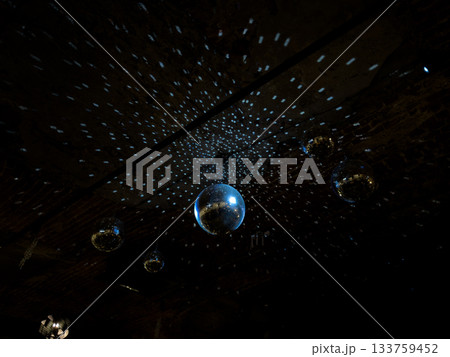 Mirrored disco ball hanging down. Retro style mirror disco balls hanging from ceiling. Large mirror ball for disco and concert for lighting effects. Ready for party or event 133759452