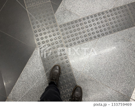 Human feet on tactile tiles for disabled. Special panel with raised dots for directional sensing. Vision problem and solution with tactile tiles. Process of using road for disabled person 133759469