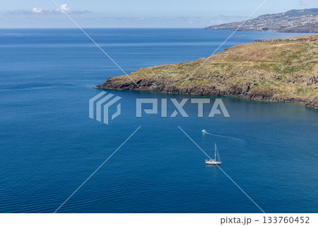 Deep blue waters of Ponta de Sao Lourenco Madeira with sailboat and soft wake near distant slope Deep blue waters of Ponta de Sao Lourenco Madeira with sailboat and soft wake near distant slope 133760452