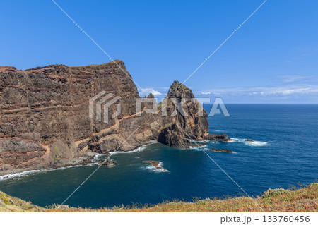 Towering cliffs at Ponta de Sao Lourenco Madeira rise above bay with rocky layers and soft plants 133760456