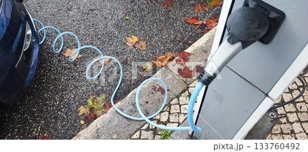 Human hand connecting an electric vehicle charging cable to a public charging station. Concept: electric vehicle infrastructure, clean energy, charging technology, eco-friendly transport. 133760492