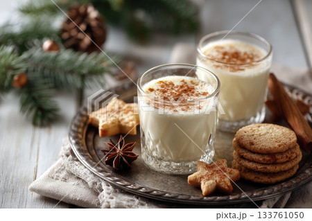 Eggnog Christmas milk cocktail with cinnamon, served in two glasses on vintage tray with shortbread star shape sugar cookies Eggnog Christmas milk cocktail with cinnamon, served in two glasses on vintage tray with shortbread star shape sugar cookies 133761050