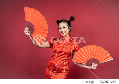 Happy Chinese girl in Cheongsam holding traditional paper fans in studio Happy Chinese girl in Cheongsam holding traditional paper fans in studio 133761347