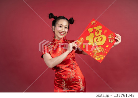 Lucky Chinese girl in traditional dress displaying calligraphy for prosperity. Lucky Chinese girl in traditional dress displaying calligraphy for prosperity. 133761348