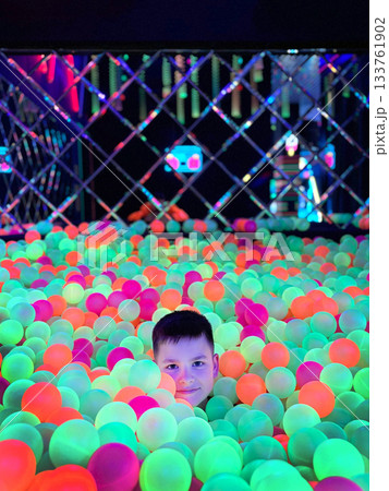Boy playing in glowing neon ball pit Boy playing in glowing neon ball pit 133761902