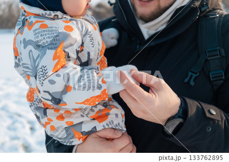 Parent Holding Baby in Winter Clothing Outdoors Parent Holding Baby in Winter Clothing Outdoors 133762895