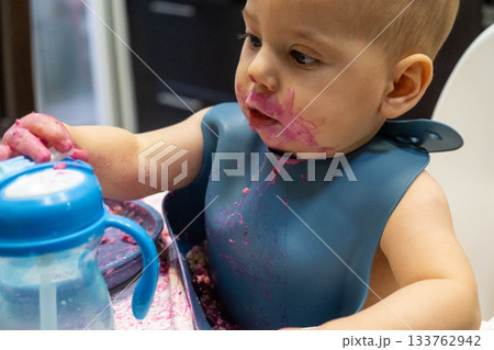 Baby Enjoying a Messy Meal in High Chair Baby Enjoying a Messy Meal in High Chair 133762942
