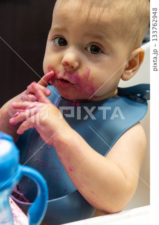 Baby Enjoying a Messy Meal in High Chair 133762948
