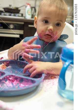 Baby Enjoying a Messy Meal in High Chair Baby Enjoying a Messy Meal in High Chair 133763003