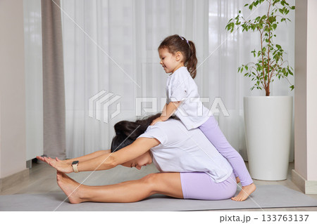 Mother and daughter bonding during a playful yoga session on a mat 133763137