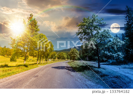 old road through forest in mountains. day and night time change concept. summer landscape with clouds above the distant ridge with sun and moon. beech trees along the path. equality and shift template 133764182