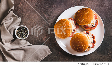 Burgers with grilled sausage and coleslaw on a plate top view web banner 133764604