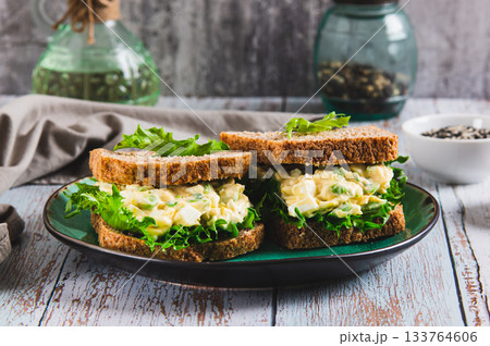 Savory egg salad sandwich with avocado on whole grain bread on a plate Savory egg salad sandwich with avocado on whole grain bread on a plate 133764606