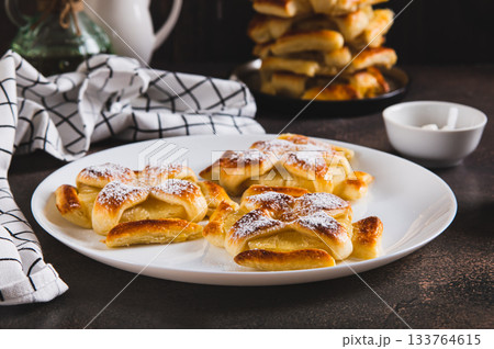 Sweet puff pastries with pineapple in powdered sugar on the table 133764615