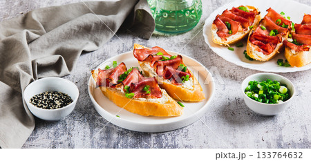Baked sandwiches with cream cheese, prosciutto and herbs on a plate on the table web banner Baked sandwiches with cream cheese, prosciutto and herbs on a plate on the table web banner 133764632